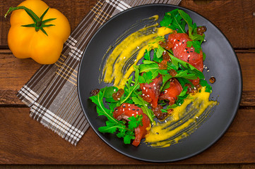 Salad from salmon, arugula, red caviar and Dutch sauce Hollandez . Wooden rustic background. Top view. Selective focus