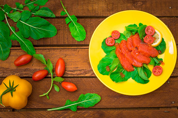 Fresh salmon with lemons and spinach on a wooden rustic background. Top view. Selective focus