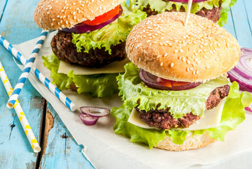 Picnic, Fast food. Unhealthy food. Delicious Fresh Tasty Burgers with Beef Cutlet, fresh Vegetables and Cheese on old rustic blue wooden table with sweet soda water. Copy space