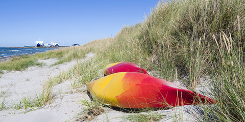 Laesoe / Denmark: Two colorful canoes lying in the dunes near the ferry terminal in Vesteroe Havn