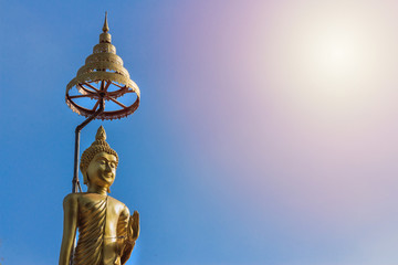 gold Buddha statue and blue sky under the sun
