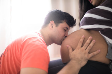 Young father kissing the pregnant wife's belly