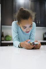 Girl in kitchen looking at smartphone