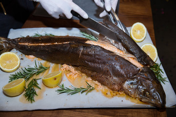 the waiter hands in white gloves cutting fish in the restaurant