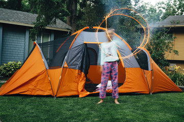 Girl in front of tent making shapes with sparklers