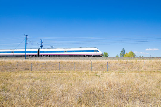 Fototapeta locomotive of fast speed train on railway in a landscape with blue sky in countryside of Spain, Europe  