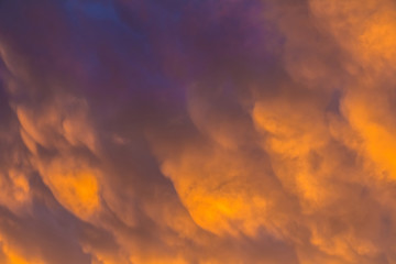 Beautiful cloudscape with colorful contrasting mammatus clouds at sunset
