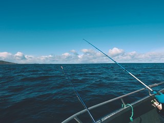 Sea fishing from steel fishing boat on open water. Rocky island et horizon.