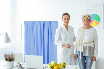 Smiling nutritionist measuring patient