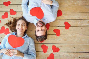 Couple lying on the wooden floor with hearts view from above. Valentine's Day.