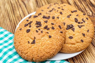Cookies with chocolate on plate with kitchen towel on the table.