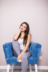 Relaxing woman sitting comfortable in sofa chair smiling happy looking at camera.