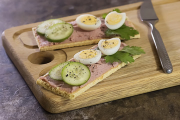 Fresh homemade meat pate on over crispbread on wooden board.