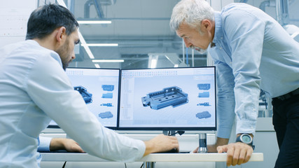 Two engineers working on computer in factory