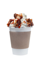 coffee in a paper cup with whipped cream, chunks of chocolate and caramel topping on a white...