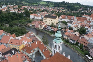 Fototapeta na wymiar View of the charming medieval town, Cesky Krumlov, from the castle tower. Looking over the town from high up, Church of St Jost overlooking the Vltava River flowing through the town.