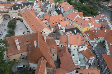 Naklejka premium Looking down on the red rooftops of the vernacular houses of the medieval town Cesky Krumlov in Czech Republic. Looking down on city from high vantage point. View from a tower looking below at city.