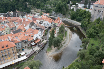 Fototapeta na wymiar View of the charming medieval town, Cesky Krumlov, from the castle tower looking down on the Vltava River. Tourists eating and drinking beer at restaurants along the river.