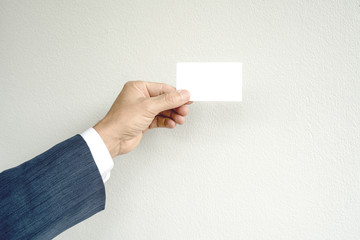 Business man hand holding name card on gray background.
