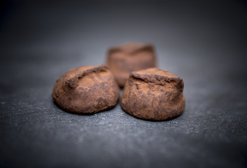 Delicious, yummy and indulgent home made luxury chocolate truffles resting on a black slate background