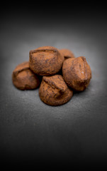 Delicious, yummy and indulgent home made luxury chocolate truffles resting on a black slate background