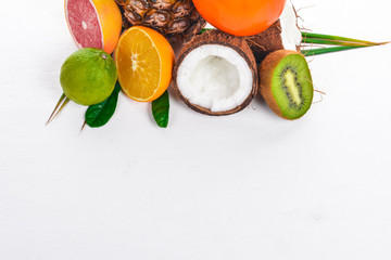 Fresh Tropical Fruits. Pineapple, coconut, kiwi, orange, pomegranate, grapefruit. On a wooden background. Top view. Free space for text.