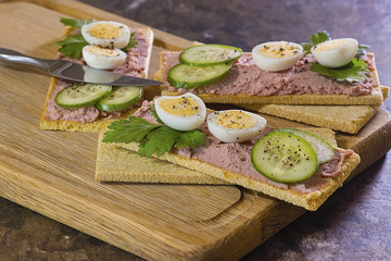 Fresh homemade meat pate on over crispbread on wooden board.