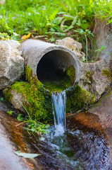 Naklejka na ściany i meble pipe from the ground flowing ecological clean water