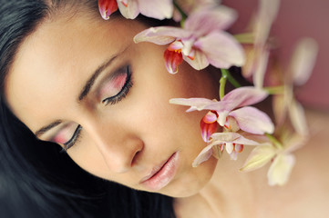 young pretty woman with flower orchid, makeup and eyeshadow 