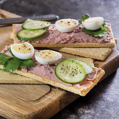 Fresh homemade meat pate on over crispbread on wooden board