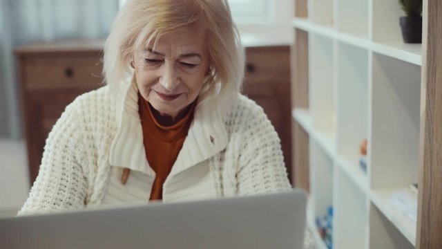 Close up face happy elder woman use laptop typing in home senior adult computer smiling internet old elder close up holiday middle online female lady portrait slow motion