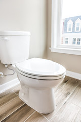 Minimalist modern clean white toilet in restroom with window in model house, home or apartment
