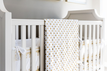 Closeup of bright yellow baby crib in nursery room in model staging home, apartment or house