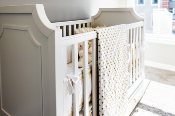 Closeup of bright yellow baby crib in nursery room in model staging home, apartment or house, toy