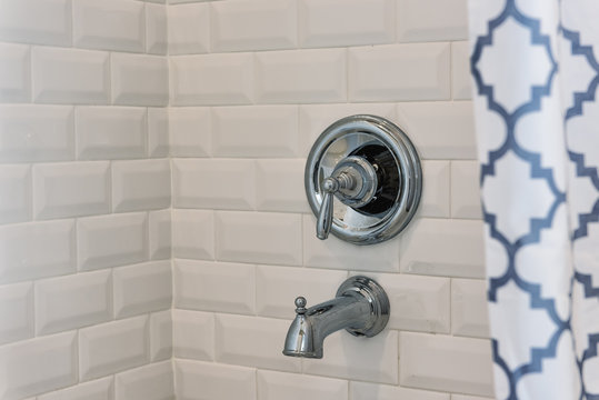 Closeup of modern white shower bath tub with blue curtains in bathroom in model home, apartment or house, tiles, faucet