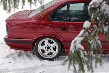 Part of a red car on a winter forest background.