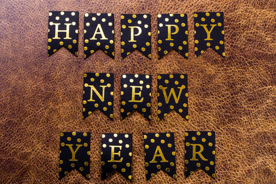 Gott nytt år skrivet med bokstävsprytt flaggspel mot läder bakgrund