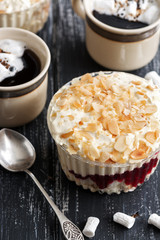 Dessert with almond blossoms and strawberry jam, coffee with marshmallows, spoon, on a wood background. Selective focus.