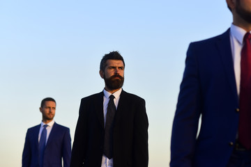 Managers wear smart suits and ties on blue sky background.