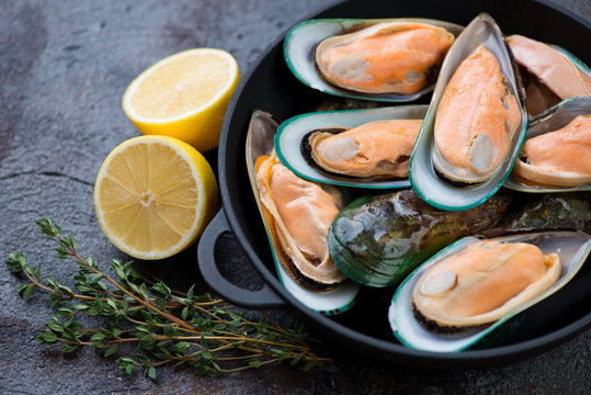 Close-up of fresh uncooked green mussels with lemon and thyme, selective focus, horizontal shot