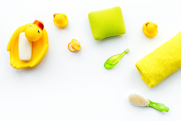 Baby bath set with yellow rubber duck. Soap, sponge, brushes, towel on white background top view copyspace