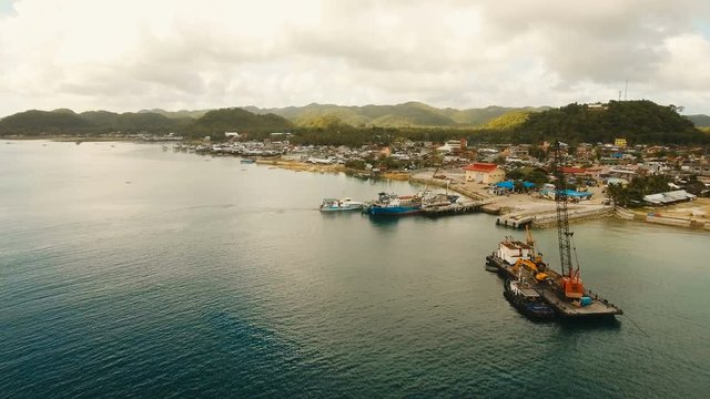 Cargo and passenger port with barges and cargo ships on tropical island. Aerial view:passenger ferry terminal Dapa city .Ferries for transport vehicles and passengers in the port. Philippines, Siargao