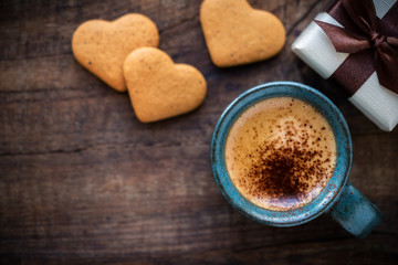 Valentine's Day background with copyspace. Romantic morning with cup of espresso coffee, heart shape cookies and a beautiful gift box on rustic wooden table
