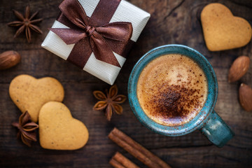 Fototapeta na wymiar Valentine's Day background with copyspace. Romantic morning with cup of espresso coffee, heart shape cookies and a beautiful gift box on rustic wooden table