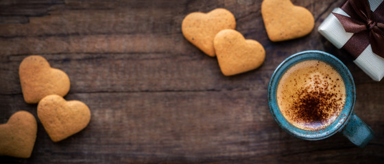 Beautiful Valentine's Day banner with copyspace. Romantic morning with cup of espresso coffee, heart shape cookies and a gift box on rustic wooden table