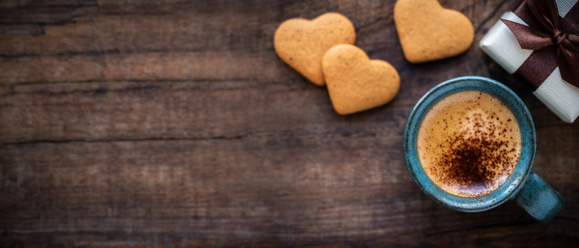 Beautiful Valentine's Day banner with copyspace. Romantic morning with cup of espresso coffee, heart shape cookies and a gift box on rustic wooden table