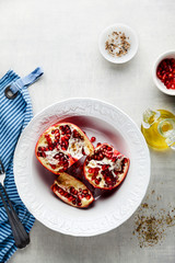 pomegranate with red seeds in a bowl on the kitchen table and food ingredients