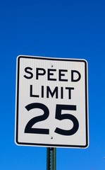 The black and white speed limit sign with the blue sky.