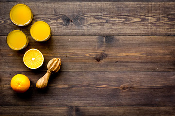 Fototapeta na wymiar Squeeze juice from oranges. Juicer and slices of oranges on dark wooden background top view copyspace