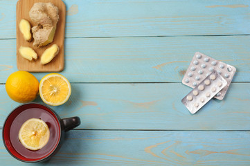 Tea mug with lemon, sliced ginger, medicine